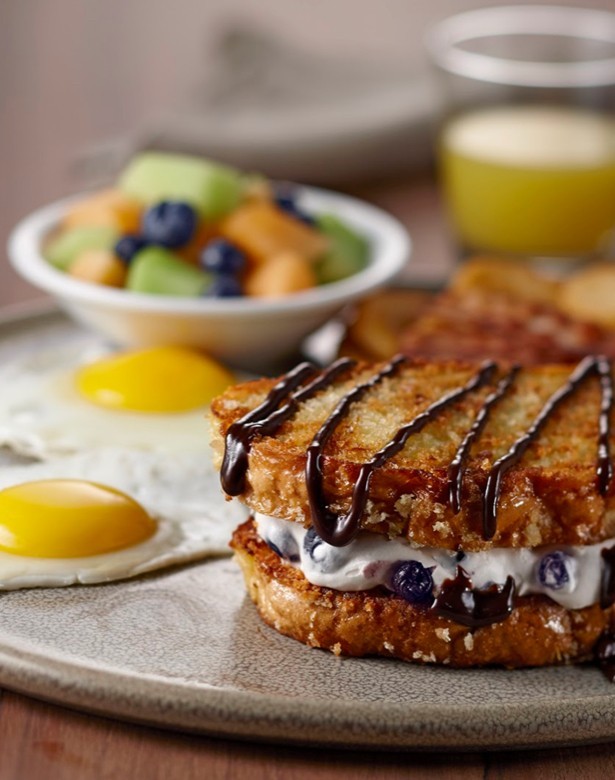 Combo eggs served with a crispy blueberry and cream cheese french toast sandwich